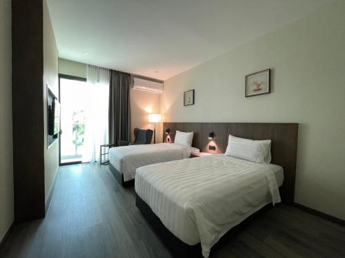 a hotel room with two beds and a window at Hotel Bundusan in Kota Kinabalu