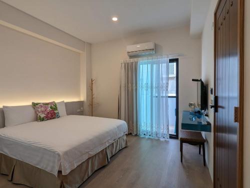 a bedroom with a bed and a desk and a window at Agape Homestay in Magong