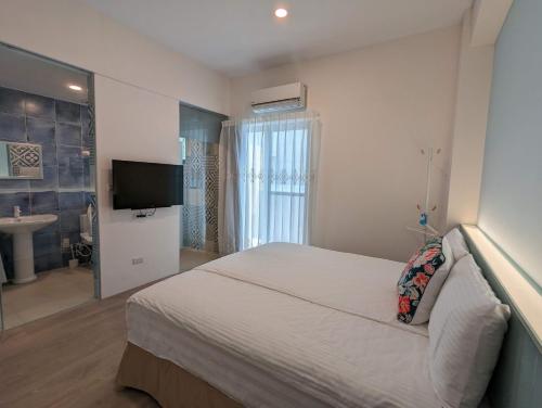 a bedroom with a bed and a television and a bathroom at Agape Homestay in Magong