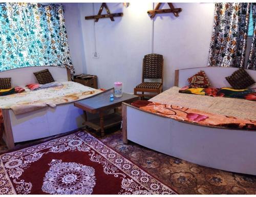 Gulab Resort, Srinagar في سريناغار: غرفة بسريرين وطاولة فيها