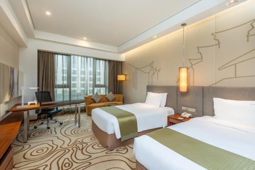 a hotel room with two beds and a desk at Holiday Inn Shanghai Hongqiao, an IHG Hotel in Shanghai