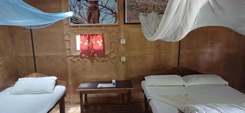 a room with two beds and a table and windows at Bardia hostel in Bhurkīā