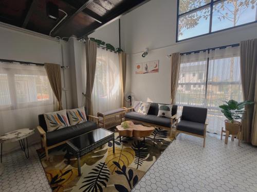 a living room with couches and tables and windows at Blessing Moon Pool Villa Khaoyai in Ban Tha Wua Tai