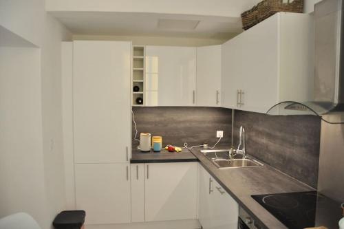 a kitchen with white cabinets and a sink at Unique apartment in the old town, near the beach in Menton