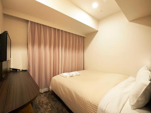 a hotel room with a bed and a television at Sotetsu Fresa Inn Kitahama in Osaka