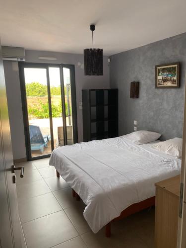 een slaapkamer met een bed en een glazen schuifdeur bij Villa avec piscine privée 10mn de la mer 4couchages in Saint-Laurent-de-la-Salanque