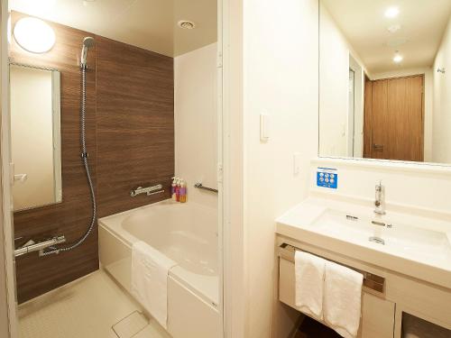 a bathroom with a tub and a sink and a shower at Sotetsu Fresa Inn Kitahama in Osaka