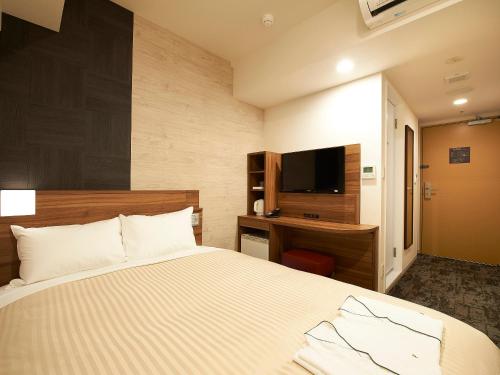 a bedroom with a bed and a desk and a television at Sotetsu Fresa Inn Kitahama in Osaka