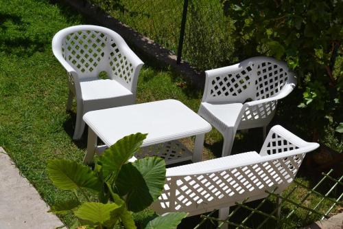 two white chairs and a table in the grass at Apartments Milosevic in Bar