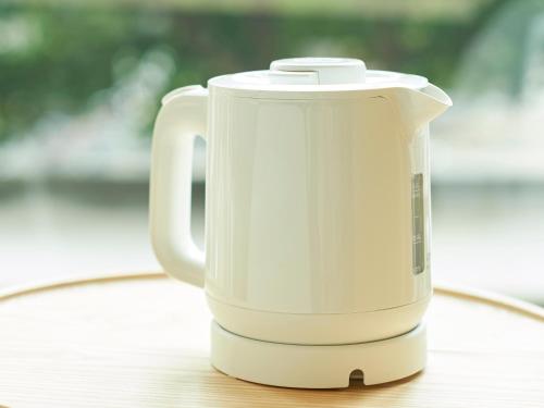 a white electric kettle sitting on a wooden table at Sotetsu Fresa Inn Kitahama in Osaka