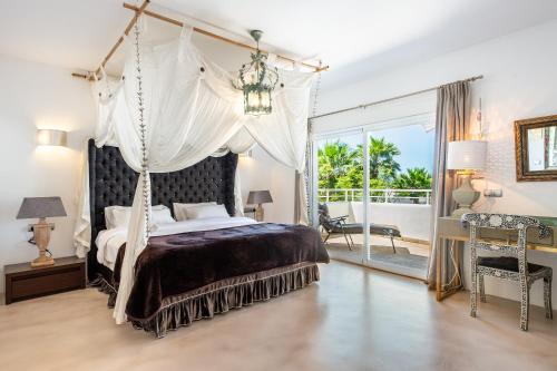 a bedroom with a canopy bed and a balcony at Villa Amarantos in Santa Eularia des Riu