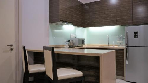 a kitchen with a counter with chairs and a refrigerator at Marina Puteri Harbour Johor by Perfect Host in Nusajaya