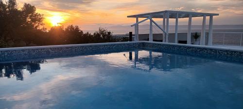 a swimming pool with a sunset in the background at Holiday home Ivo in Prigradica