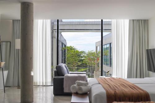 a bedroom with a bed and a chair and a large window at Sundance Dayclub Hua Hin in Hua Hin