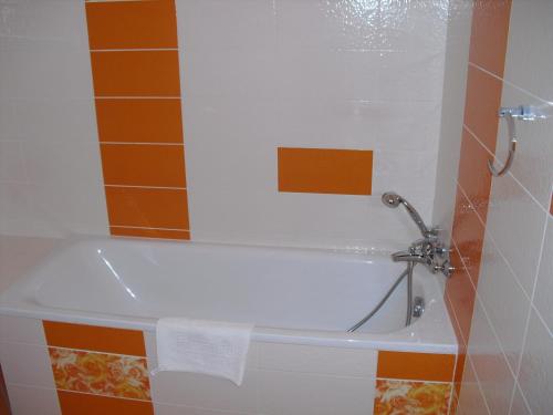 a bath tub in a bathroom with orange tiles at Městský Hotel Dorinka in Hostinné