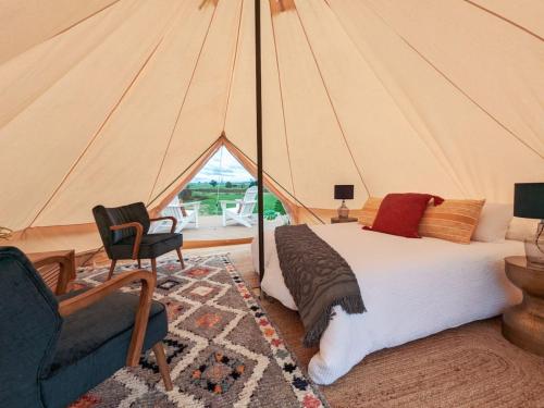 a bedroom with a tent with a bed and a chair at Glamping Vineyard Getaway with Luxury Amenities in Broke