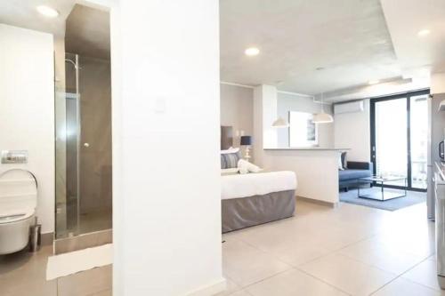 a white bathroom with a bed and a shower at Lux Holiday Apartment Sibaya in Umdloti
