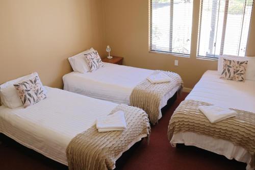 a room with three beds with towels on them at Kendenup Cottages and Lodge in Kendenup