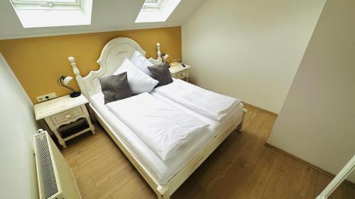 1 dormitorio con 1 cama con sábanas y almohadas blancas en Apartments Erbgericht, en Bad Schandau