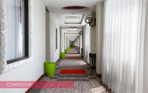 a hallway with a row of green chairs and a red rug at Ramada Suites By Wyndham Solo in Solo