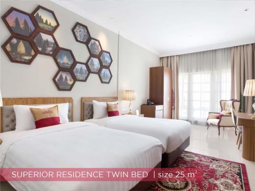 two beds in a hotel room with a mirror on the wall at Ramada Suites By Wyndham Solo in Solo