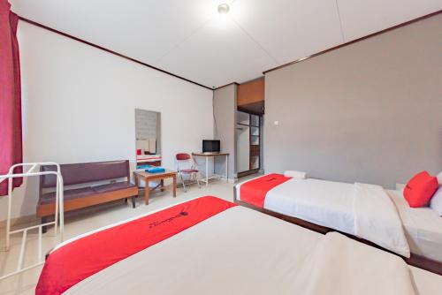 RedDoorz Syariah at Hotel Budi Family في Ciamis: غرفة فندقية بسريرين ومكتب