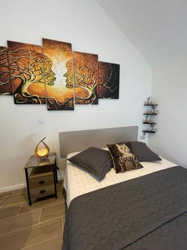 ein Schlafzimmer mit einem Bett mit vier Gemälden an der Wand in der Unterkunft nuitzen in Boyer