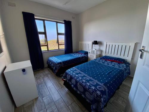 a bedroom with two beds and a window at La Corsica 7, Uvongo in Margate