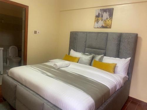 um quarto com uma cama grande com almofadas amarelas e brancas em msotsi homes 3 em Nairobi