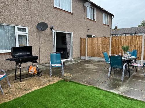 a patio with chairs and a table and a piano at Beautiful 2-bedroom in Grays close to Lakeside in Grays Thurrock