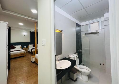 a bathroom with a sink and a toilet and a bedroom at Dalat ECO Hotel 2 in Da Lat