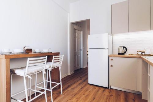 a kitchen with a white refrigerator and a counter with stools at The Repose Aesthetic Apt. R2 in Heraklio Town