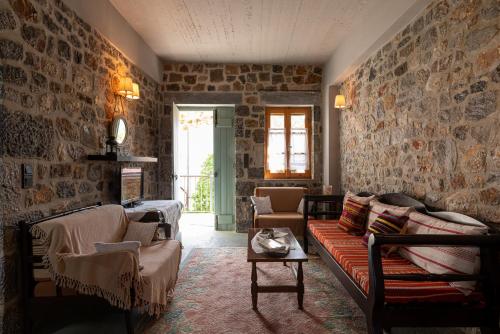 a living room with stone walls and a couch and chairs at Vasilikata in Agios Konstantinos