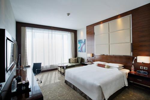 ChākanにあるCourtyard by Marriott Pune Chakanの大型ベッドとテレビが備わるホテルルームです。