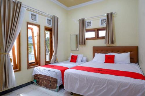 1 dormitorio con 2 camas y almohadas rojas en RedDoorz near Desa Wisata Tambi Dieng en Wonosobo