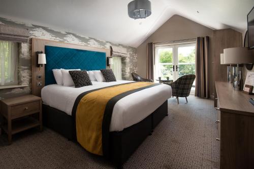 a bedroom with a large bed with a blue headboard at Windermere Rooms at The Wateredge Inn in Ambleside