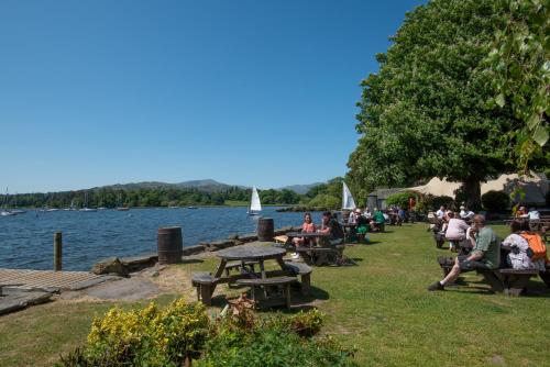 a group of people sitting on benches by the water at Windermere Rooms at The Wateredge Inn in Ambleside