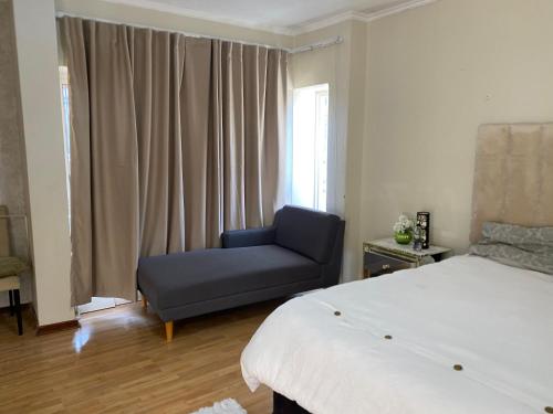 a bedroom with a bed and a blue chair at Siena Sun Guesthouse Rooms and Breakfast Option in Midrand