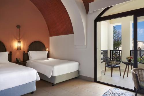 a bedroom with two beds and a balcony at The Cove Rotana Resort - Ras Al Khaimah in Ras al Khaimah
