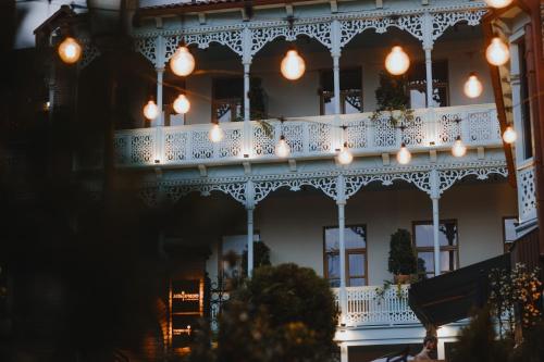 un edificio con un balcón blanco con luces encendidas en The House Hotel Old Tbilisi, en Tiflis
