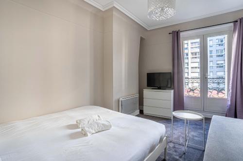 une chambre blanche avec un lit et une télévision dans l'établissement 20 - Urban Design Flat Pere Lachaise, à Paris