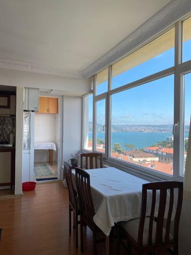 Zimmer mit einem Tisch und Stühlen sowie einem großen Fenster in der Unterkunft kireçburnu mahallesinde deniz manzaralı eşyalı daire in Istanbul
