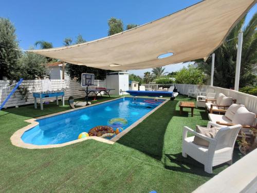 a swimming pool with an umbrella on a yard at Helios Luxury Suites in Had Nes