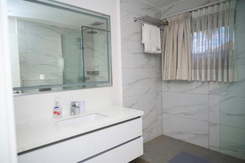 a white bathroom with a sink and a shower at White Stone Apartments Nyarutarama in Kigali