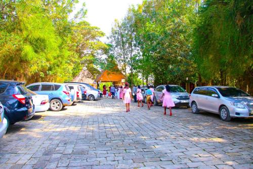 a group of people in pink dresses walking down a street at Dovenest Lodge in Naivasha