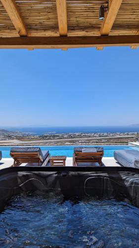 a swimming pool with chairs and the ocean in the background at Sunset Hill Suites in Mýkonos City