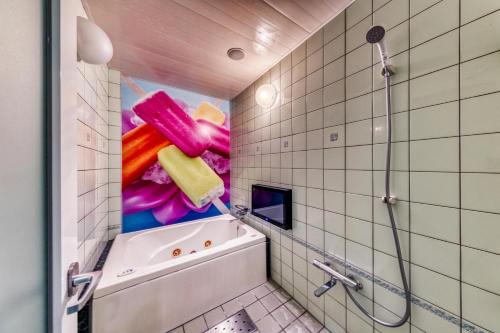 baño con bañera y una pintura en la pared en SWEETS HOTEL KYOTO -Adult Only en Yawata