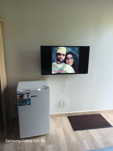 a flat screen tv on a wall next to a refrigerator at Chez Mkoudou in Ouangani