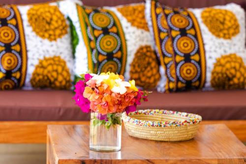 a vase of flowers sitting on a table with a bowl at Pingwe Beach Apartments in Pingwe