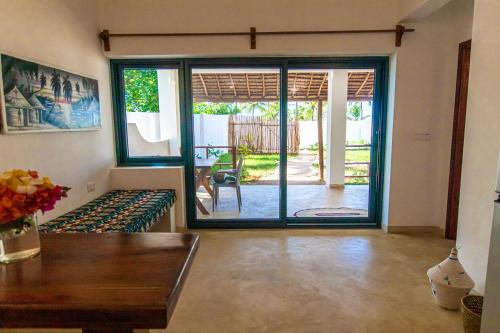 a living room with a table and a sliding glass door at Pingwe Beach Apartments in Pingwe